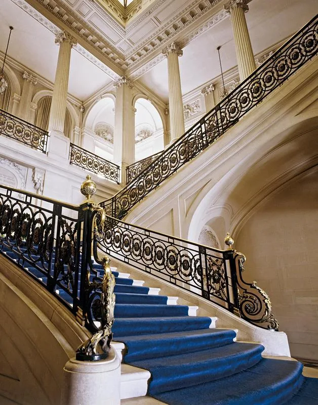 Escalier d'honneur en pierre avec rampe en fer forgé